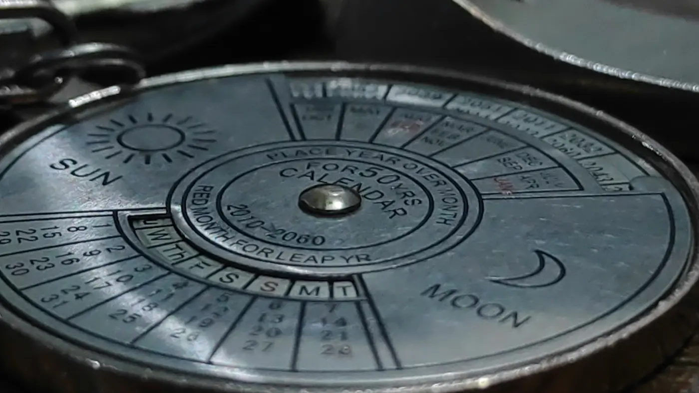 Calendrier perpétuel mécanique en métal patiné, cadran gravé indiquant Sun et Moon